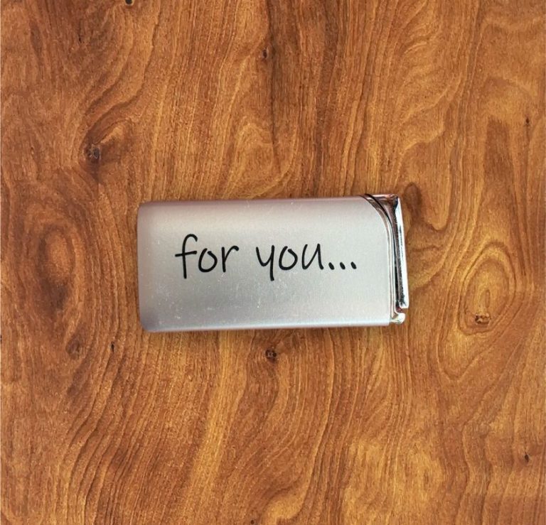 Silberner Gegenstand mit der Aufschrift "for you..." auf Holzoberfläche.